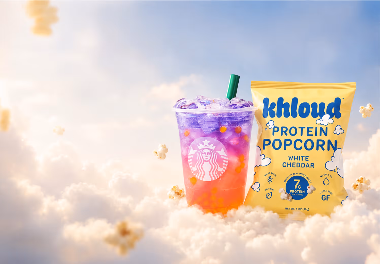 Starbucks Butterfly refresher drink sitting on a cloud in the sky next to Khloud Protein Popcorn White Cheddar in a 1oz bag, surrounded by floating pieces of popcorn